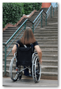 Woman in wheelchair looking at stairs.